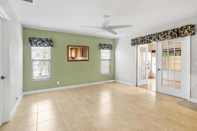 spare room featuring ceiling fan, french doors, a textured ceiling, and light tile patterned flooring