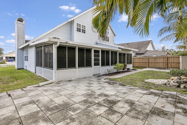 back of property featuring a patio area, a sunroom, and a lawn