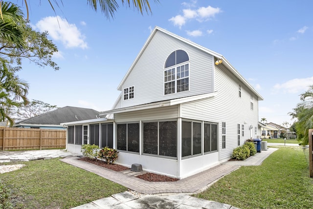 rear view of house featuring a sunroom, a yard, and central air condition unit