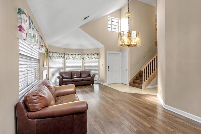 living room with high vaulted ceiling, hardwood / wood-style floors, and a notable chandelier