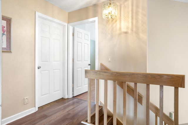 hall featuring wood-type flooring and a chandelier