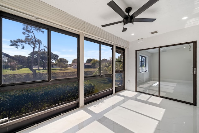 unfurnished sunroom with ceiling fan