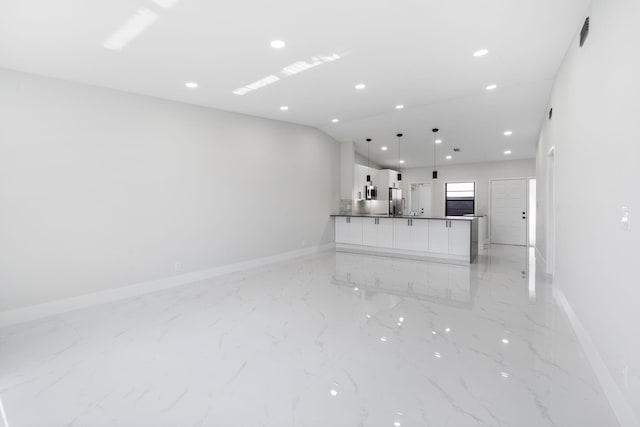 kitchen with hanging light fixtures, stainless steel fridge, white cabinets, and a kitchen island