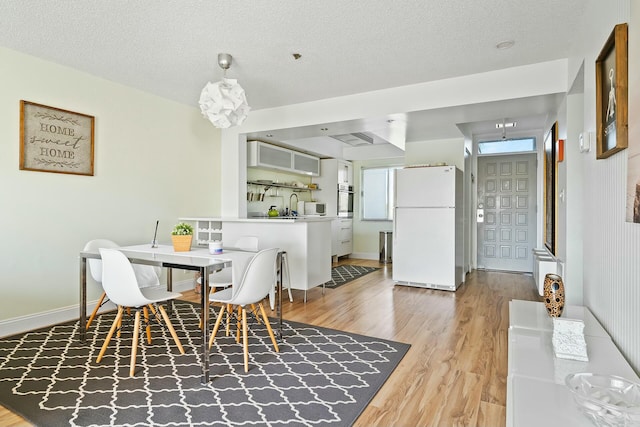 dining space featuring light hardwood / wood-style flooring and a textured ceiling