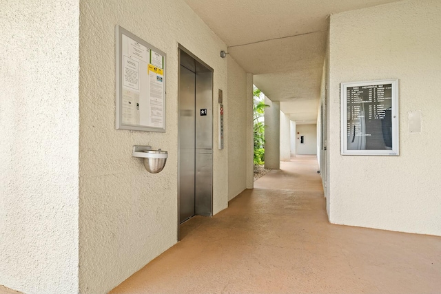 hallway with concrete flooring and elevator