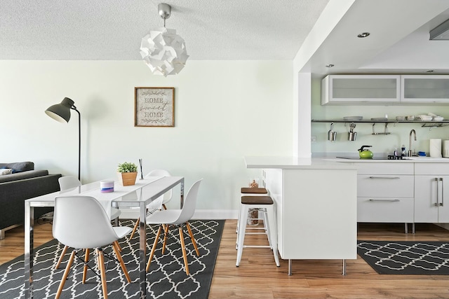 dining room with sink, a textured ceiling, and light hardwood / wood-style floors