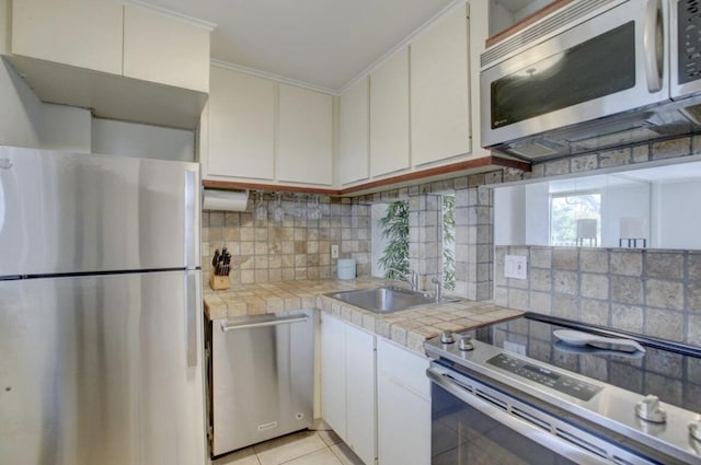 kitchen featuring white cabinetry, appliances with stainless steel finishes, tile counters, and sink