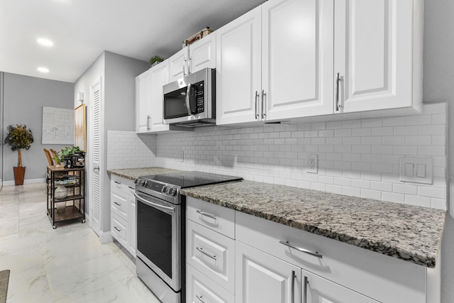 kitchen with marble finish floor, appliances with stainless steel finishes, stone countertops, white cabinets, and baseboards