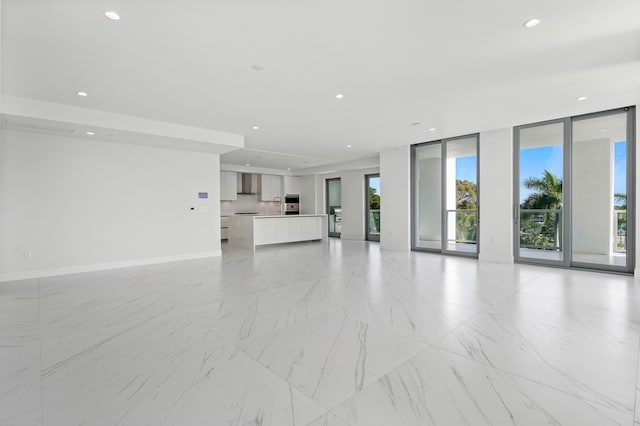 unfurnished living room with a wall of windows, recessed lighting, a sink, and baseboards