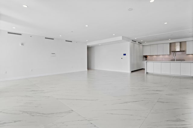 unfurnished living room featuring baseboards, visible vents, a sink, and recessed lighting