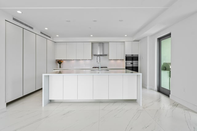 kitchen featuring light countertops, wall chimney exhaust hood, modern cabinets, and white cabinets