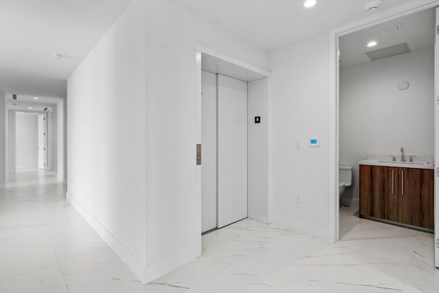 hall featuring baseboards, elevator, marble finish floor, a sink, and recessed lighting