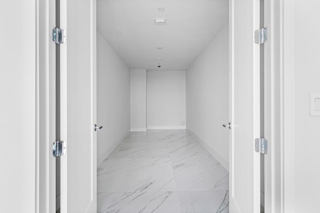 hall with marble finish floor and baseboards