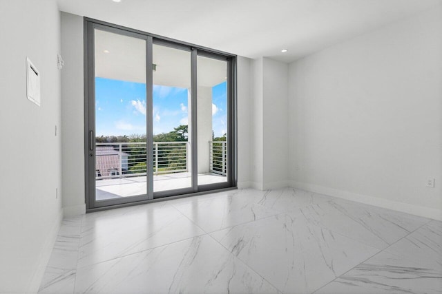 empty room with marble finish floor, a wall of windows, and baseboards