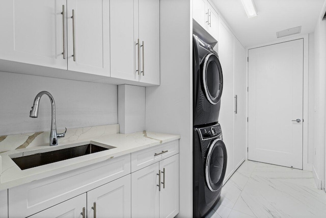 laundry room featuring stacked washing maching and dryer, cabinet space, marble finish floor, and a sink