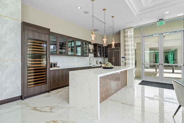 bar featuring beverage cooler, decorative light fixtures, marble finish floor, french doors, and a sink