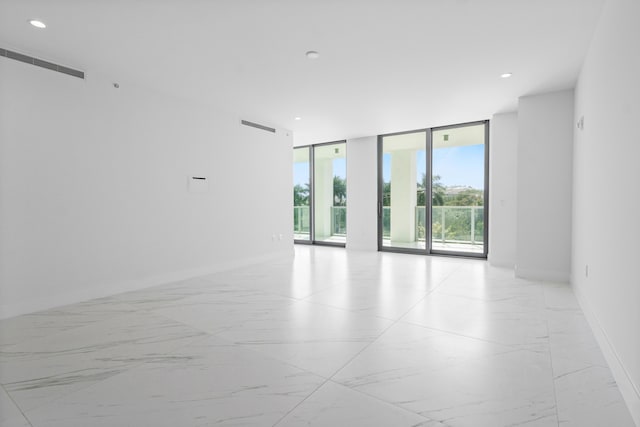 empty room with baseboards, expansive windows, visible vents, and recessed lighting