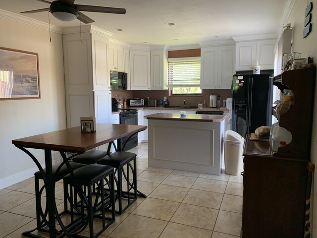 kitchen with white cabinetry, ornamental molding, light tile patterned floors, and black appliances