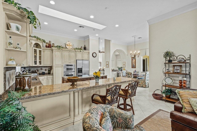 kitchen featuring appliances with stainless steel finishes, a skylight, hanging light fixtures, kitchen peninsula, and cream cabinetry