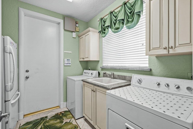 clothes washing area featuring light tile patterned flooring, sink, cabinets, separate washer and dryer, and a textured ceiling