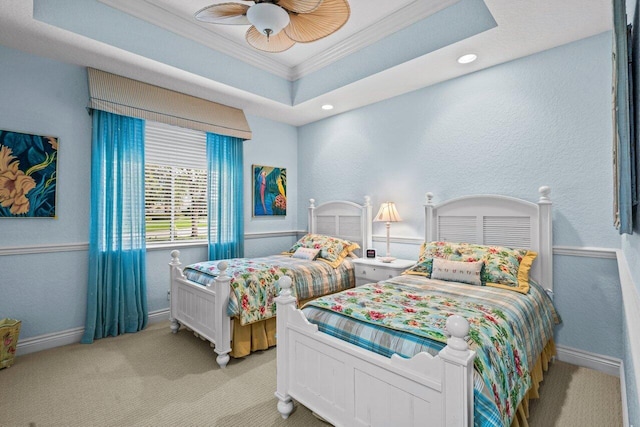 bedroom with ceiling fan, ornamental molding, a tray ceiling, and light carpet