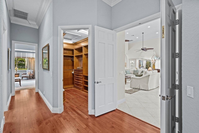 hallway featuring crown molding, light hardwood / wood-style floors, and a high ceiling