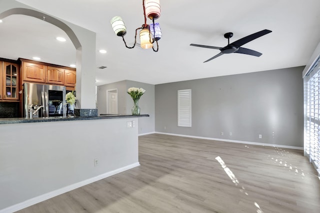 kitchen with ceiling fan, stainless steel fridge, light hardwood / wood-style floors, and dark stone countertops