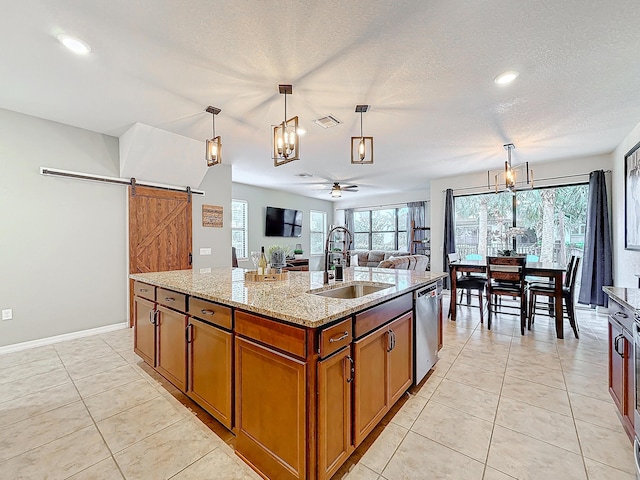 kitchen featuring pendant lighting, a barn door, sink, and a center island with sink