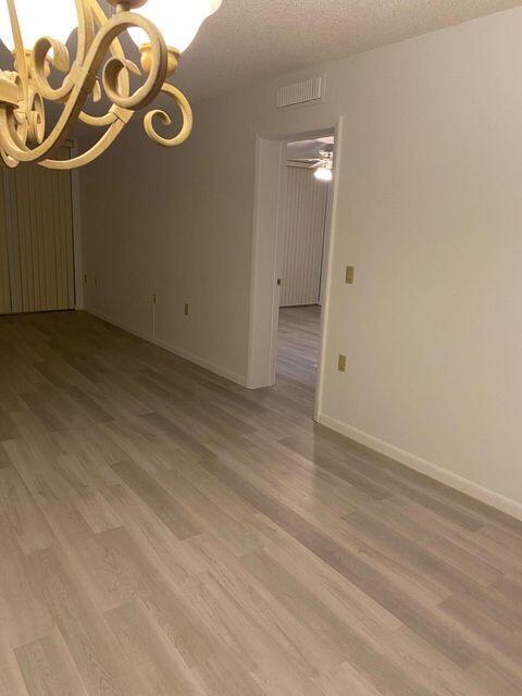 empty room featuring a chandelier, hardwood / wood-style floors, and a textured ceiling