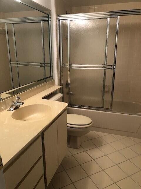 full bathroom with enclosed tub / shower combo, vanity, tile patterned floors, and toilet