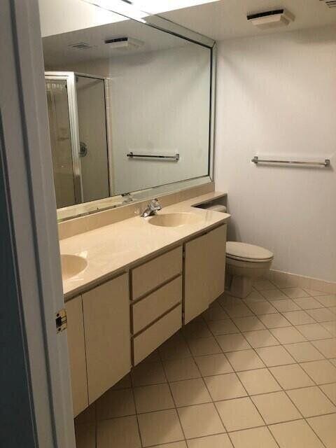 bathroom featuring an enclosed shower, vanity, tile patterned floors, and toilet