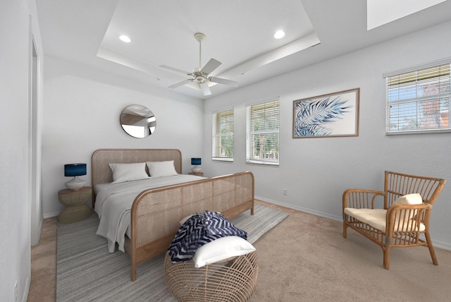 bedroom featuring recessed lighting, a raised ceiling, light colored carpet, and baseboards