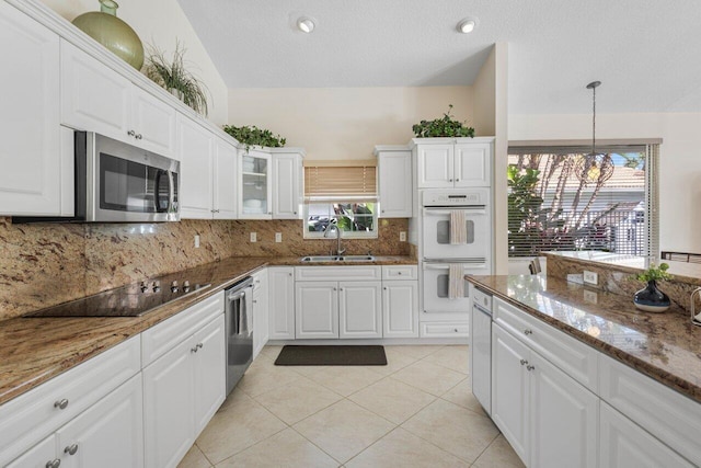 kitchen with light tile patterned floors, a sink, white cabinetry, appliances with stainless steel finishes, and decorative backsplash