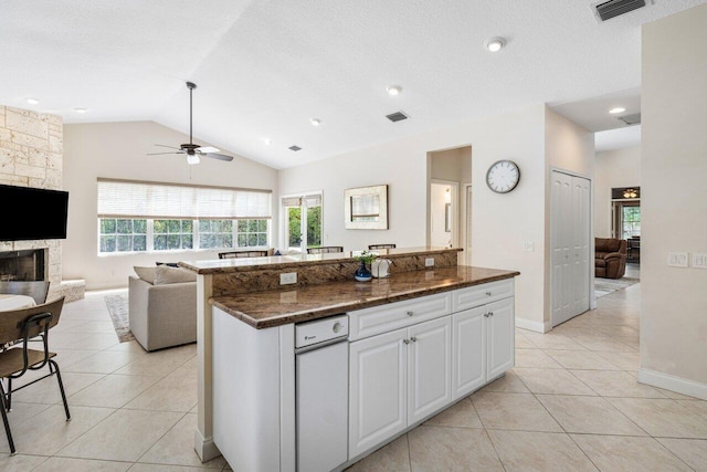 kitchen featuring open floor plan, a stone fireplace, light tile patterned flooring, and visible vents