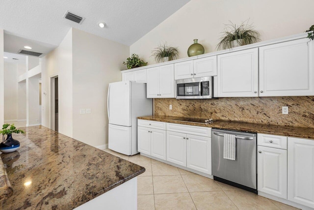 kitchen featuring visible vents, lofted ceiling, stainless steel appliances, white cabinetry, and light tile patterned flooring