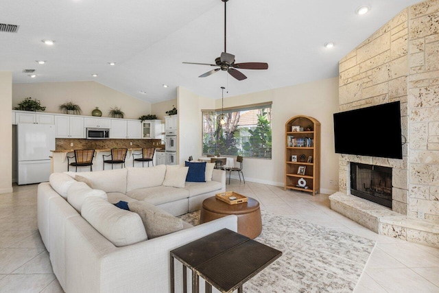 living area featuring light tile patterned floors, visible vents, vaulted ceiling, and a stone fireplace