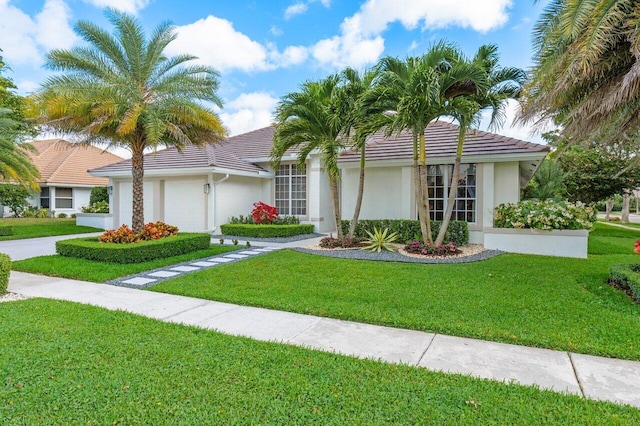 view of front of house featuring a tile roof, stucco siding, an attached garage, a front yard, and driveway