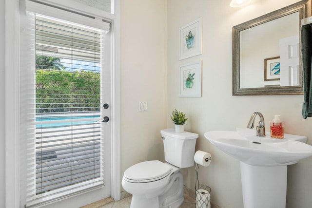 half bath with toilet, tile patterned flooring, and a sink