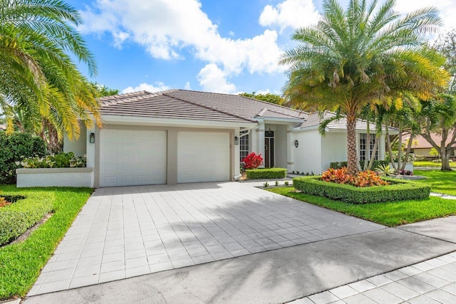 ranch-style house featuring a garage, decorative driveway, a tiled roof, and stucco siding