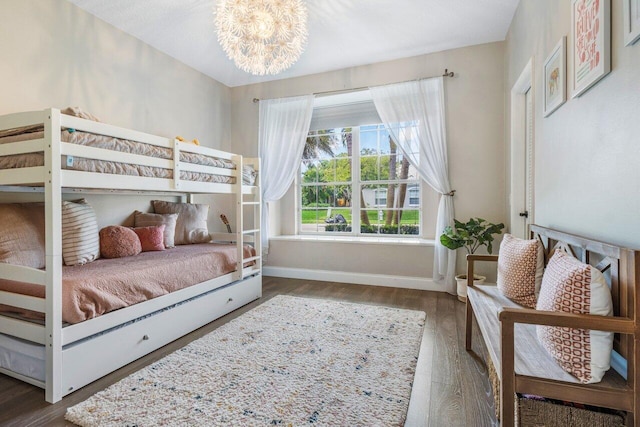 bedroom featuring an inviting chandelier, baseboards, and wood finished floors