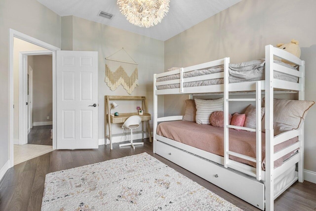 bedroom featuring a chandelier, wood finished floors, visible vents, and baseboards