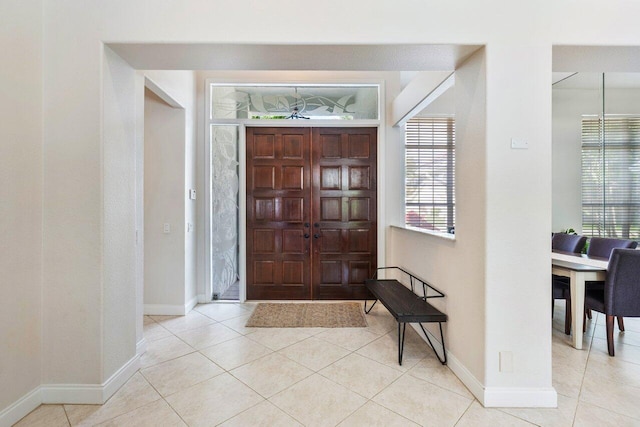 foyer entrance featuring a healthy amount of sunlight, tile patterned flooring, and baseboards