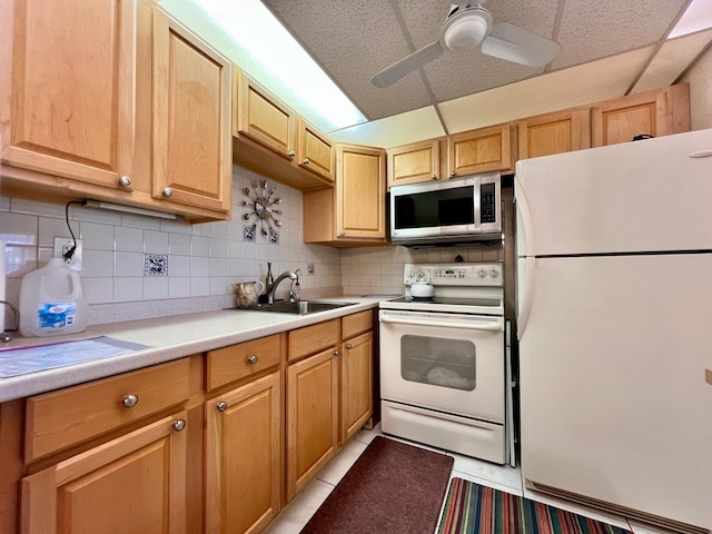 kitchen featuring white appliances, light tile patterned floors, decorative backsplash, light countertops, and a sink