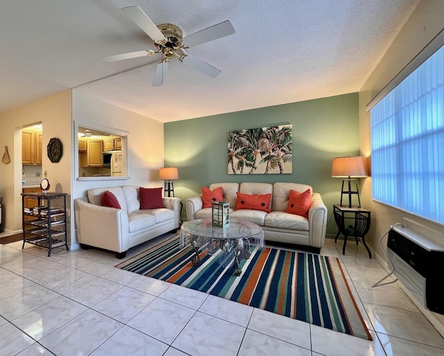 living area featuring light tile patterned flooring, ceiling fan, a textured ceiling, and baseboards