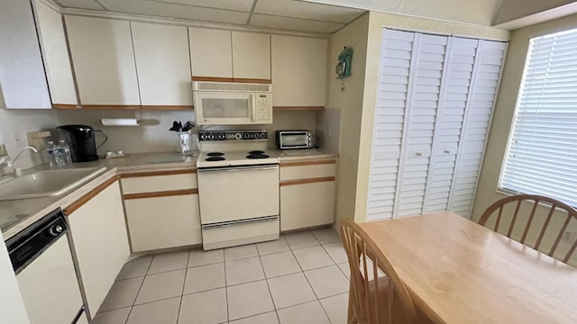 14623 Bonaire Blvd Unit 605, Delray Beach, FL 33446 - kitchen featuring white appliances, a sink, light countertops, light tile patterned flooring, and cream cabinetry