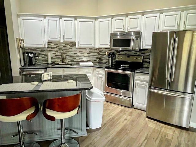 kitchen featuring sink, backsplash, white cabinets, and appliances with stainless steel finishes