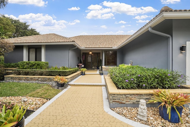 doorway to property with a tiled roof and stucco siding