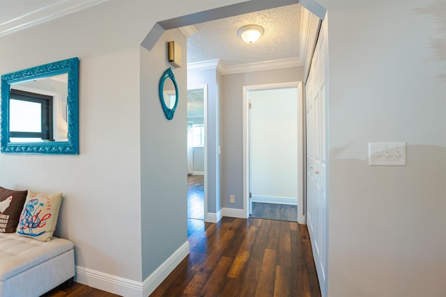 hall featuring crown molding, dark wood-type flooring, and a textured ceiling