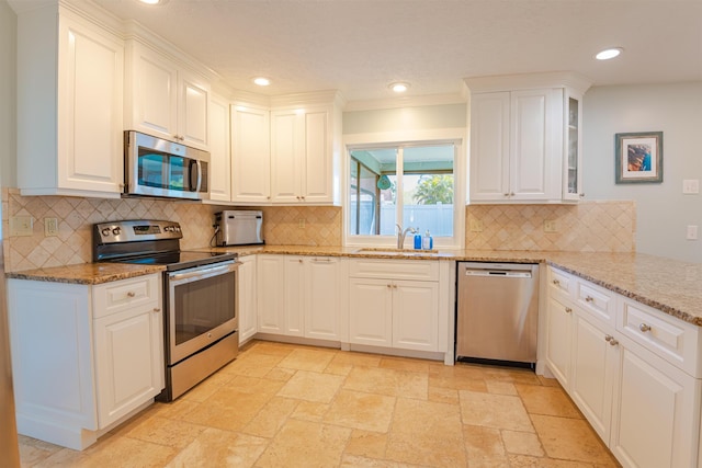 kitchen featuring sink, stainless steel appliances, light stone counters, tasteful backsplash, and white cabinets