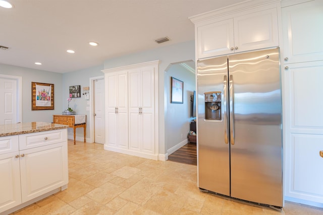 kitchen with stainless steel fridge with ice dispenser, light stone countertops, and white cabinets